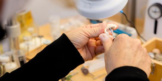 Frauenhände arbeiten an Zahnimplantat