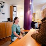 Zahnarzthelferin am Emfnag mit Patientin